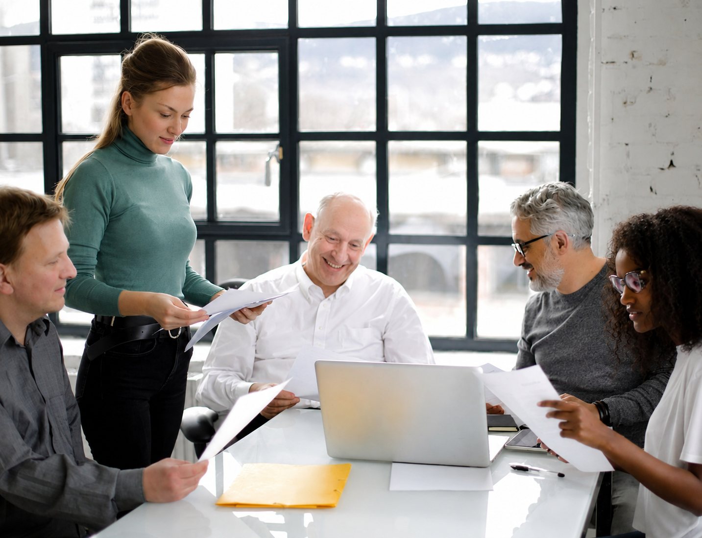 A diverse engineering team working together around a laptop in a bright loft office